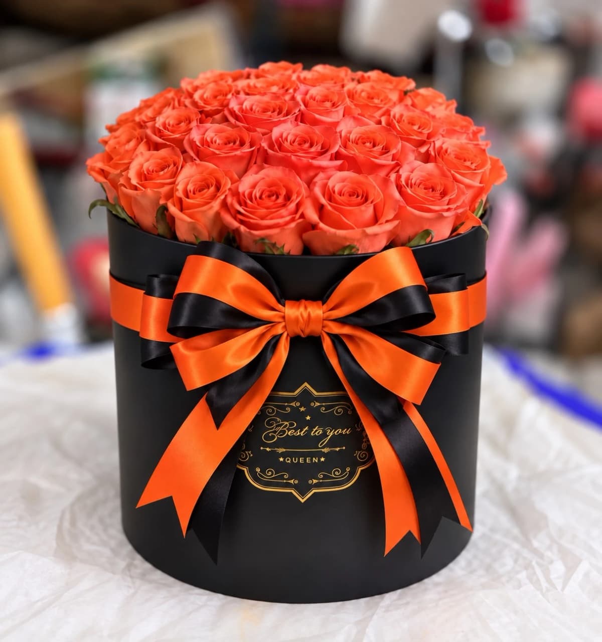 Elegant Orange Rose Box with Orange roses arranged in a round shape, presented in a black box with an orange ribbon.