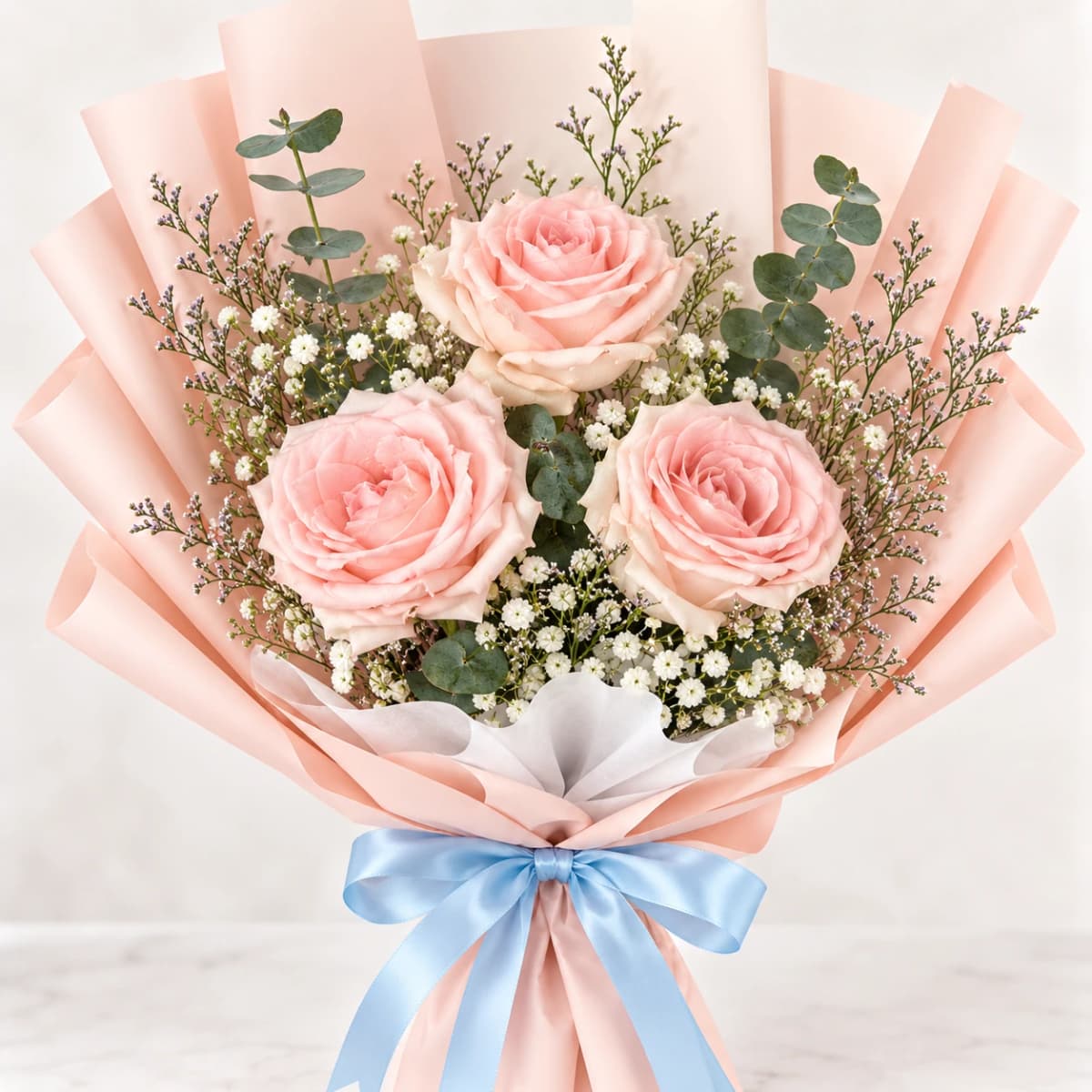 Three pink roses bouquet wrapped in pink paper.